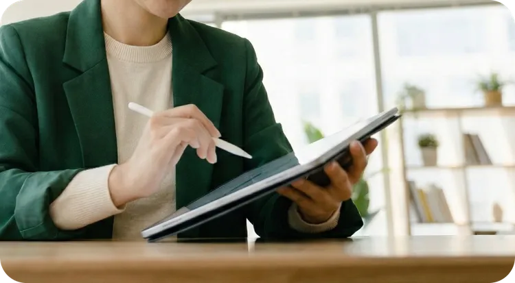 A woman signing her handwritten signature on a tablet using a white digital pen.