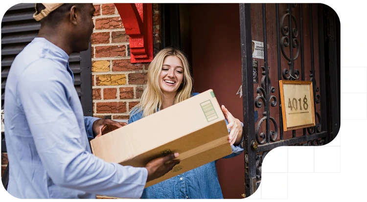 Person delivering a large package to a smiling woman at her front door.