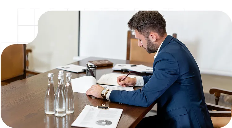 Hombre revisando y firmando documentos en una mesa de reuniones.