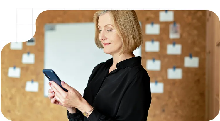 Mujer usando un teléfono móvil en un entorno profesional, consultando información digital.
