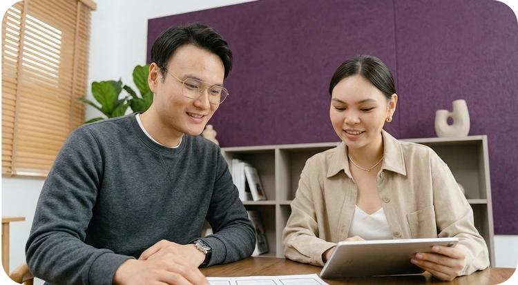 Two people reviewing and signing documents digitally on a tablet during a business meeting.