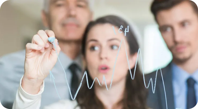 Team of professionals analyzing sales trends on a whiteboard.